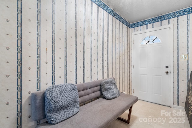 foyer entrance featuring light tile patterned floors, a textured ceiling, and wallpapered walls