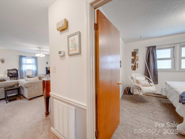 carpeted bedroom with ceiling fan and a textured ceiling