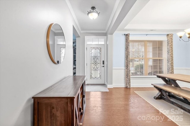 foyer featuring ornamental molding, wood-type flooring, and a notable chandelier