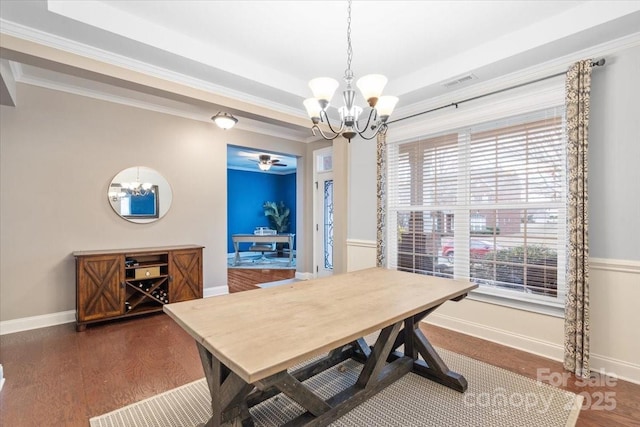 dining room featuring dark wood-type flooring, ornamental molding, and ceiling fan with notable chandelier