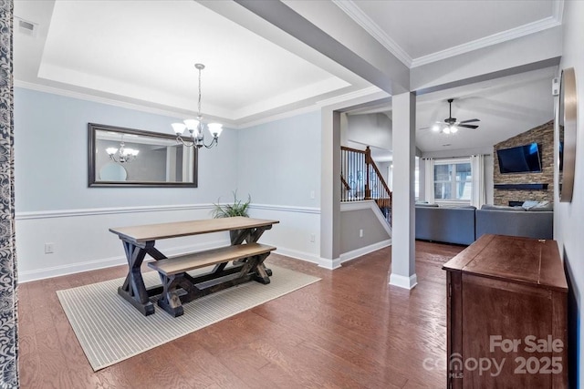 dining area with dark wood-type flooring, a tray ceiling, and ceiling fan with notable chandelier