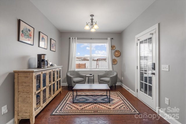 living area with dark hardwood / wood-style floors and a notable chandelier