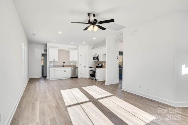 kitchen with sink, ceiling fan, appliances with stainless steel finishes, white cabinetry, and light wood-type flooring