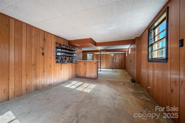 spare room with bar area and wood walls