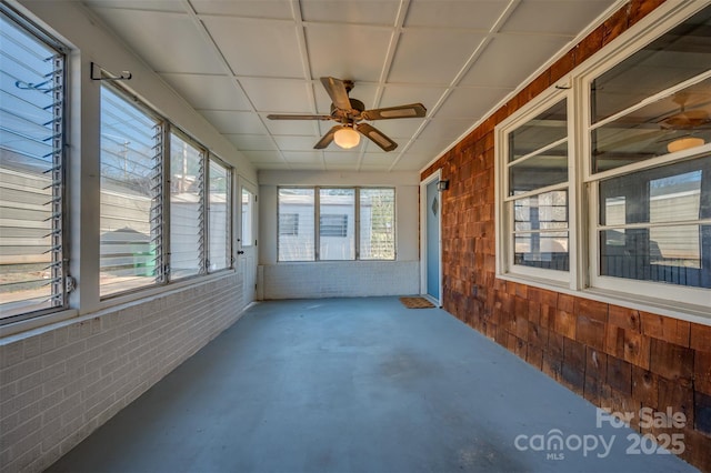 unfurnished sunroom featuring ceiling fan and a paneled ceiling