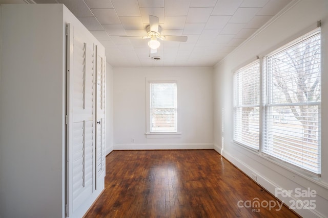 empty room featuring dark hardwood / wood-style flooring, crown molding, and ceiling fan