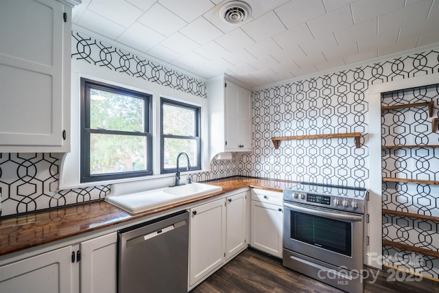 kitchen featuring appliances with stainless steel finishes, sink, white cabinets, ornamental molding, and dark wood-type flooring