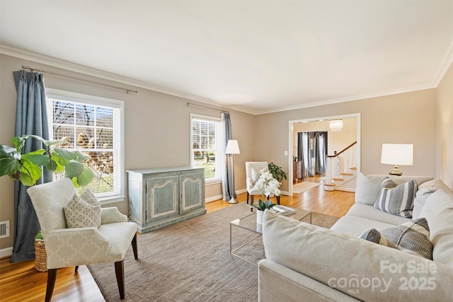 living area with baseboards, visible vents, wood finished floors, stairs, and crown molding