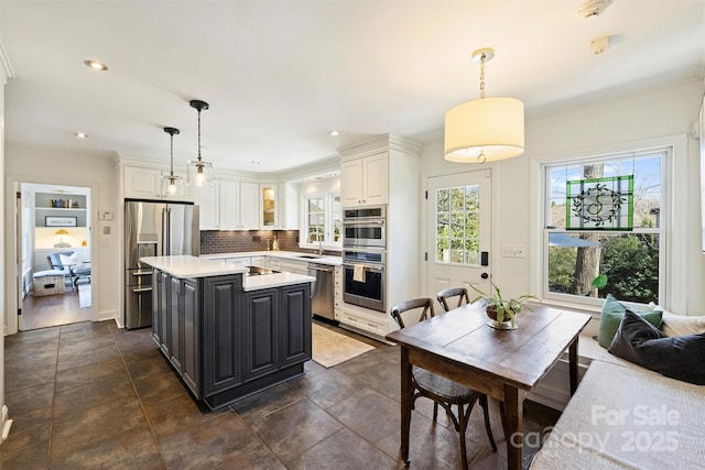 kitchen with a sink, white cabinetry, light countertops, appliances with stainless steel finishes, and decorative backsplash