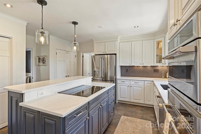 kitchen with appliances with stainless steel finishes, white cabinets, backsplash, and a center island