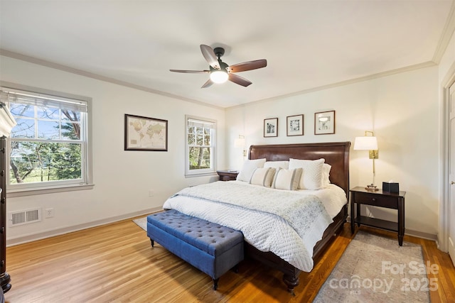 bedroom featuring baseboards, visible vents, wood finished floors, and ornamental molding