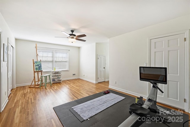 workout area featuring light wood-style floors, ceiling fan, and baseboards