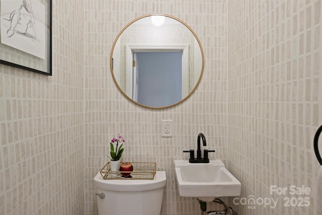 bathroom featuring toilet, a sink, and tile walls