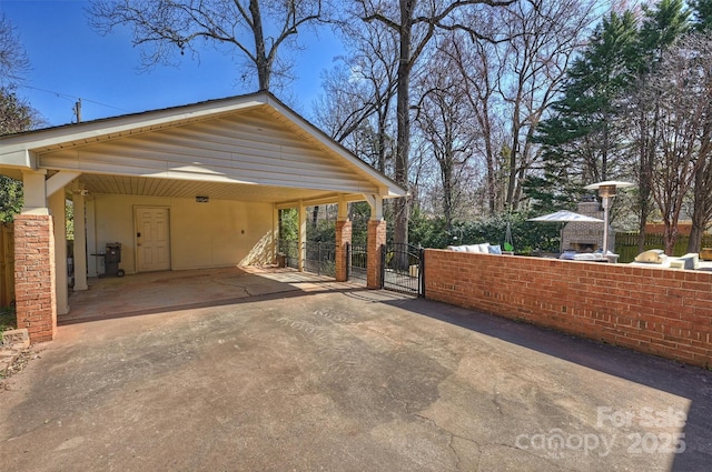 exterior space with concrete driveway, an outdoor kitchen, fence, and a gate