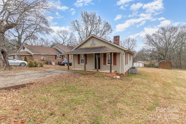 view of front of home featuring a porch, a storage unit, central AC unit, and a front yard