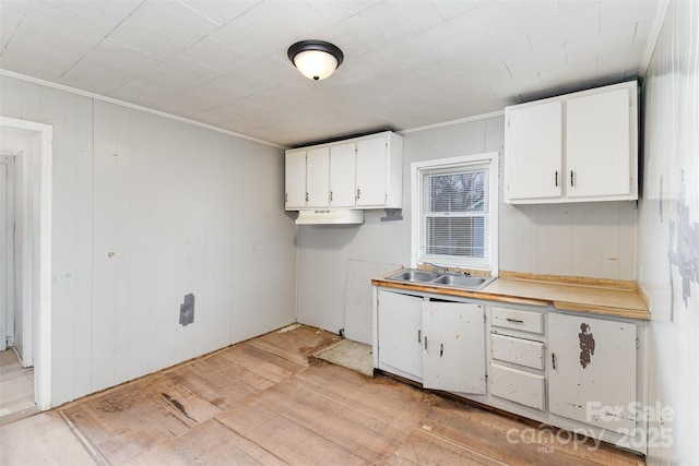 kitchen with white cabinetry, ornamental molding, sink, and light wood-type flooring