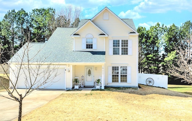 traditional-style house featuring concrete driveway, an attached garage, and a shingled roof