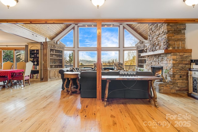 living room with beam ceiling, wooden ceiling, a fireplace, and light hardwood / wood-style flooring