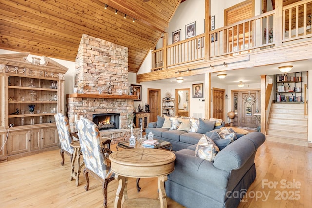 living room featuring wood ceiling, a fireplace, high vaulted ceiling, and light wood-type flooring