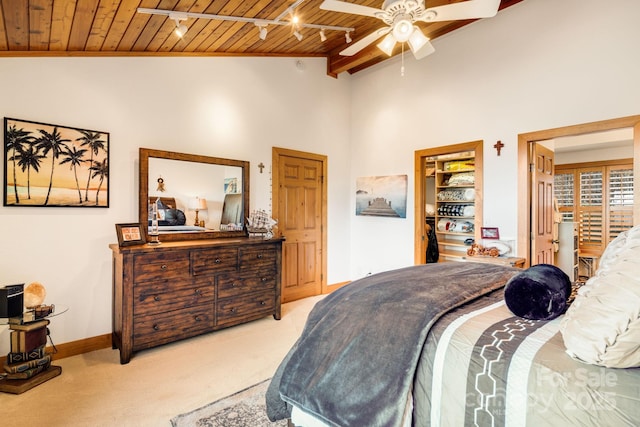 carpeted bedroom with rail lighting, ceiling fan, wooden ceiling, and high vaulted ceiling