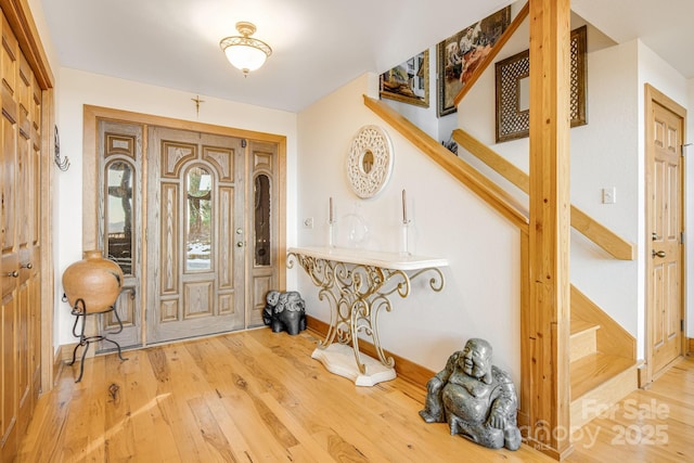 foyer with baseboards, wood finished floors, and stairway