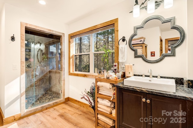 full bathroom featuring baseboards, vanity, wood finished floors, and a stall shower