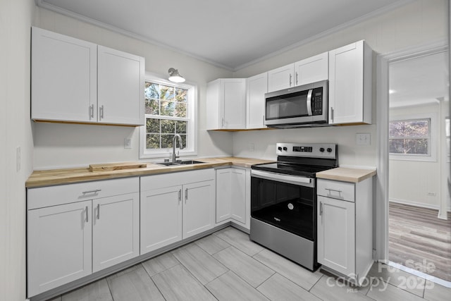 kitchen featuring butcher block counters, sink, white cabinets, stainless steel appliances, and crown molding