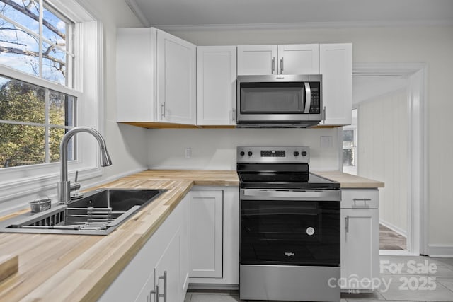 kitchen featuring stainless steel appliances, butcher block countertops, sink, and white cabinets