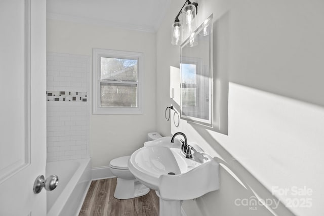 bathroom with hardwood / wood-style flooring, crown molding, tiled shower / bath combo, and toilet