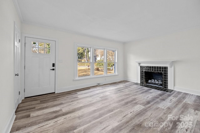 unfurnished living room featuring crown molding, a tile fireplace, and light hardwood / wood-style floors