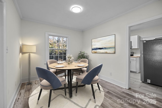 dining space with ornamental molding and light hardwood / wood-style flooring