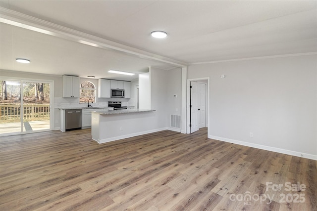 kitchen featuring light stone countertops, wood-type flooring, stainless steel appliances, and kitchen peninsula