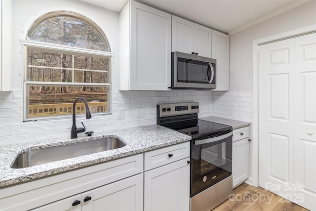 kitchen with white cabinetry, sink, light stone countertops, and appliances with stainless steel finishes