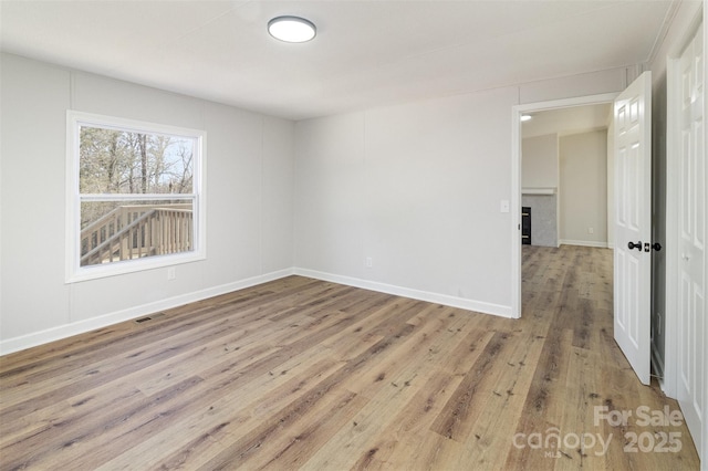 spare room with a tile fireplace and light hardwood / wood-style flooring