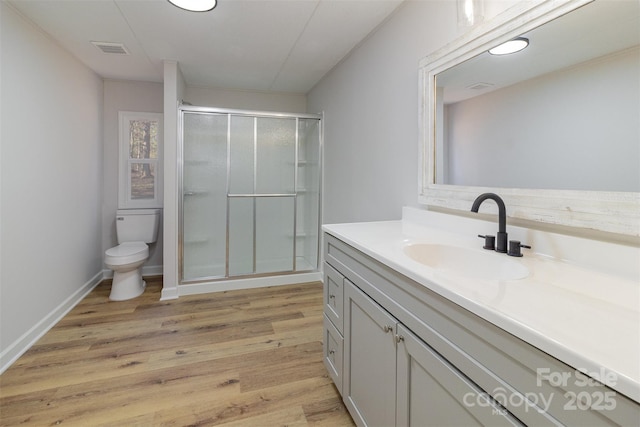 bathroom featuring vanity, a shower with shower door, wood-type flooring, and toilet