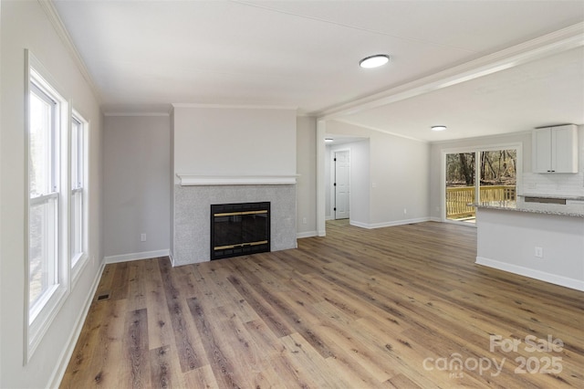 unfurnished living room featuring ornamental molding, wood-type flooring, and a tile fireplace