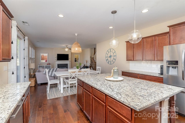 kitchen with stainless steel refrigerator with ice dispenser, a center island, dark hardwood / wood-style flooring, pendant lighting, and backsplash