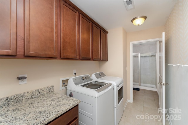 clothes washing area with cabinets, light tile patterned floors, and independent washer and dryer