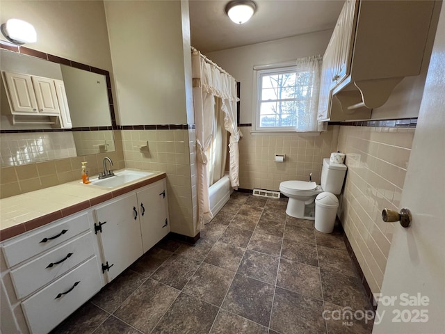 full bathroom with vanity, toilet, tile walls, and shower / bath combo