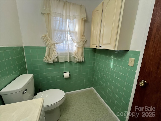 bathroom with tile walls, vanity, and toilet