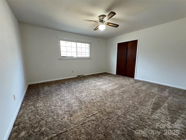 unfurnished bedroom featuring ceiling fan, dark carpet, and a closet