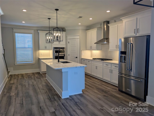 kitchen featuring white cabinetry, a center island with sink, pendant lighting, stainless steel appliances, and wall chimney range hood