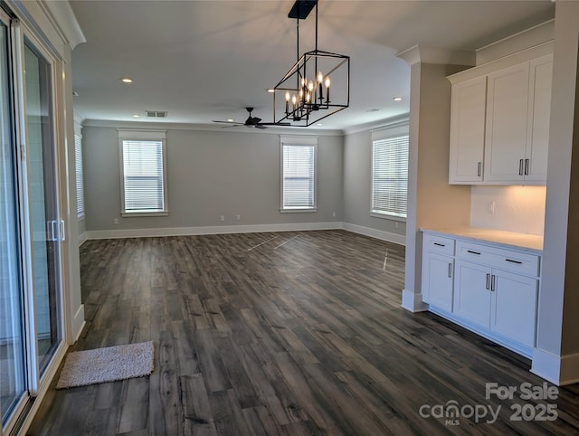 unfurnished dining area with crown molding, dark wood-type flooring, and ceiling fan