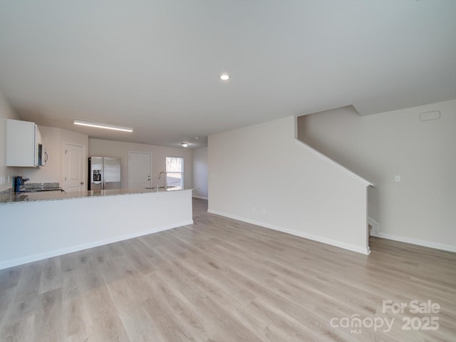 unfurnished living room with sink and light hardwood / wood-style flooring