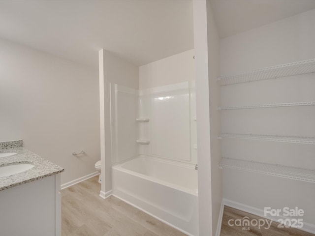 full bathroom with wood-type flooring, toilet, shower / washtub combination, and vanity