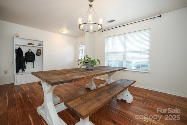 dining space with dark hardwood / wood-style floors and a notable chandelier