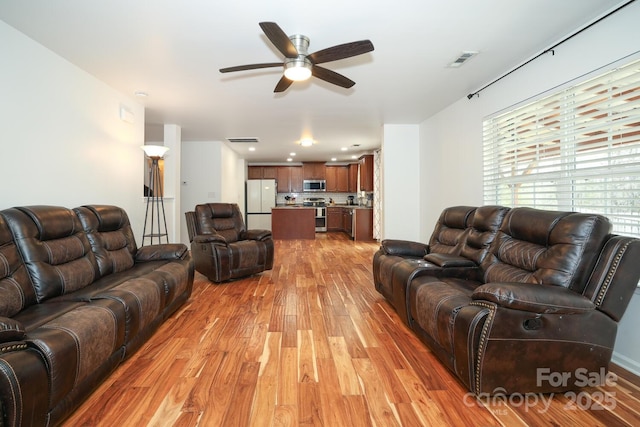 living room with ceiling fan and light hardwood / wood-style flooring