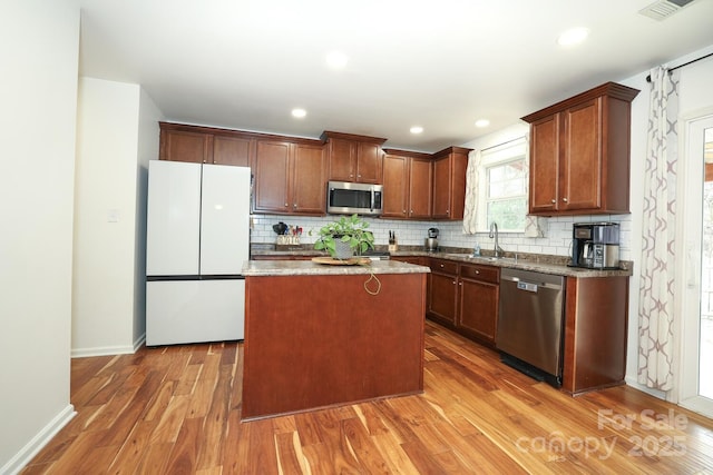 kitchen featuring stainless steel appliances, a center island, hardwood / wood-style floors, and backsplash