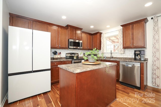 kitchen featuring a kitchen island, wood-type flooring, appliances with stainless steel finishes, and sink