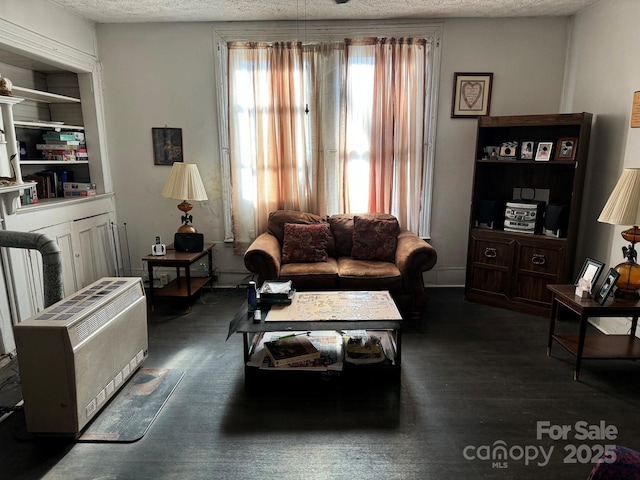 living room with heating unit and a textured ceiling